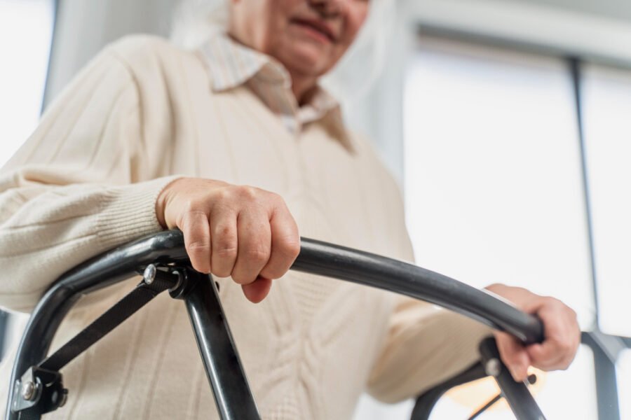 Elderly woman using a walker to promote mobility and mental health.