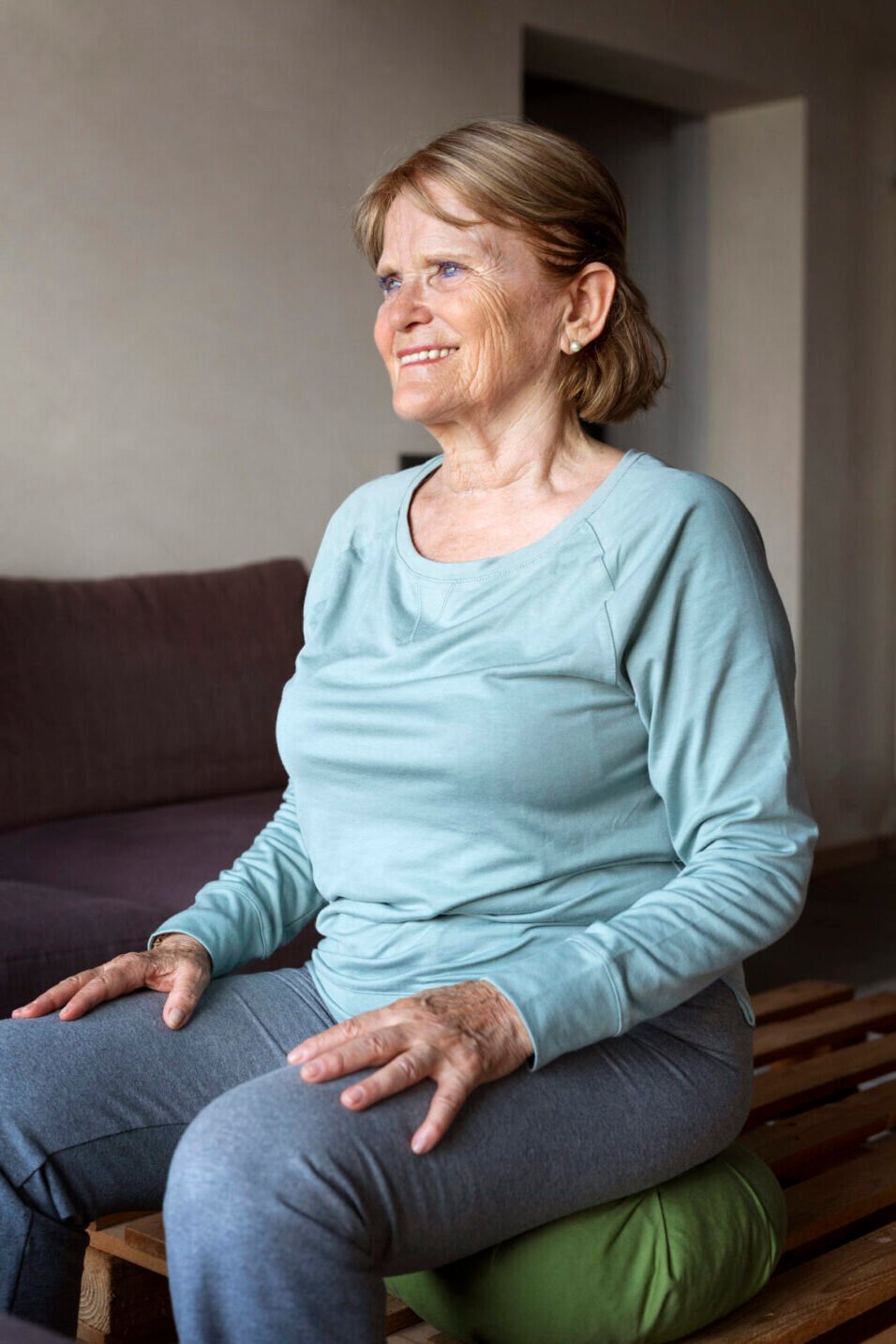 Elderly woman practicing seated yoga for health benefits at home.
