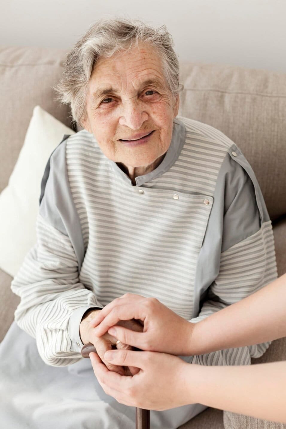 Elderly woman smiling and holding hands with caregiver, highlighting the benefits of WalkPort for se.