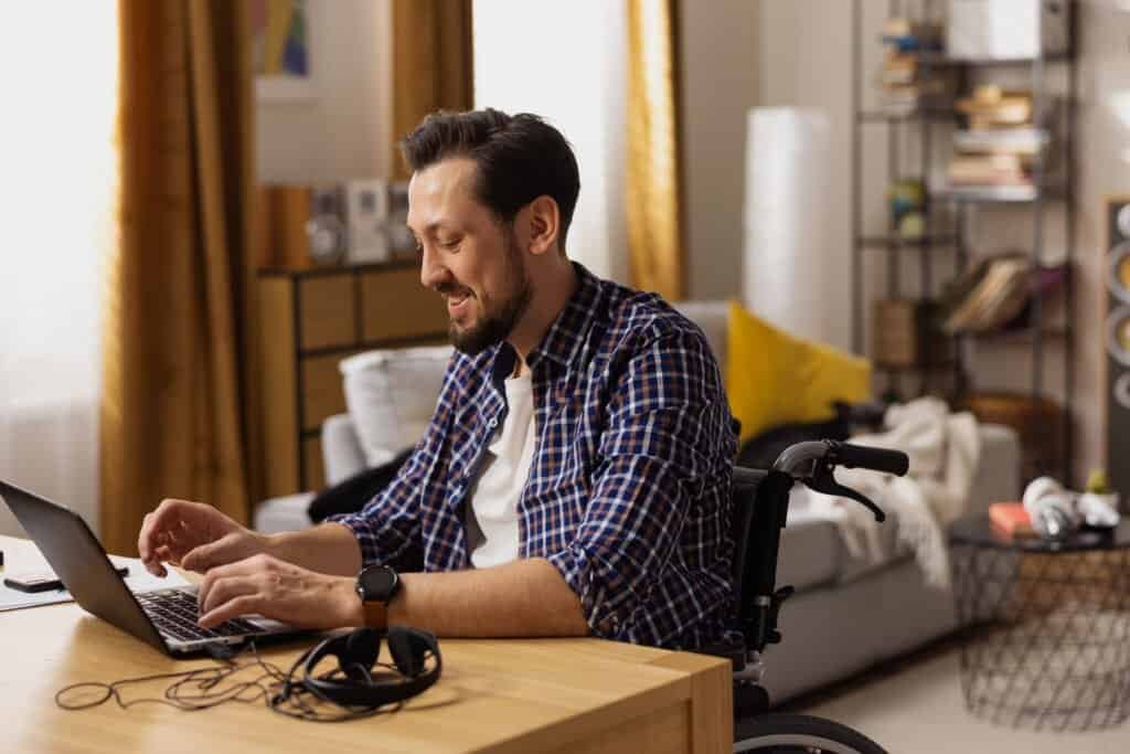 Man working on a laptop at home using assistive technology for accessibility.