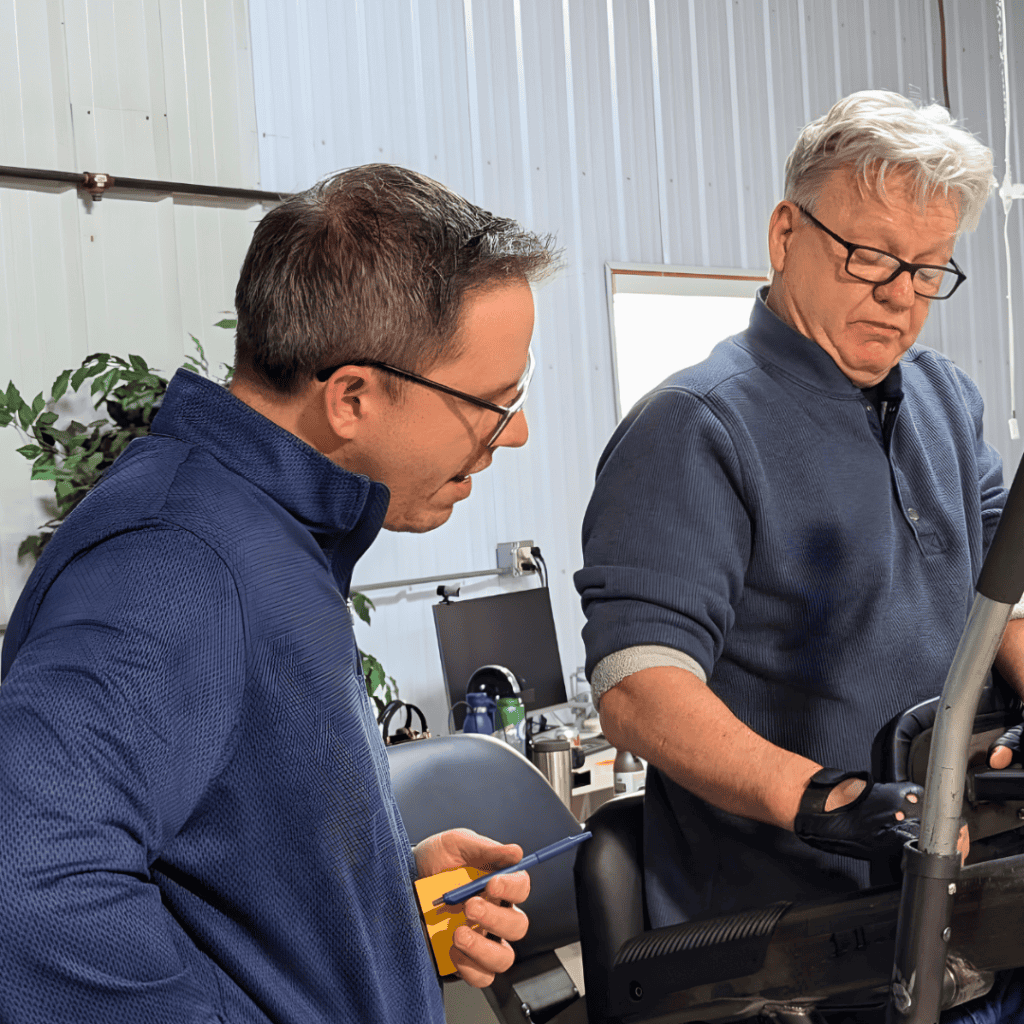 Two men reviewing technical equipment in a workshop setting.
