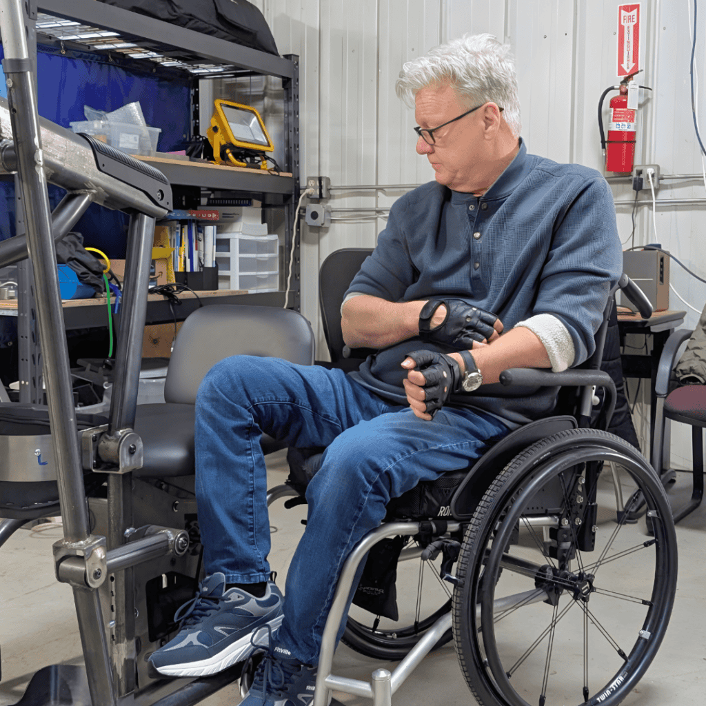 Wheelchair user working on a project in a workshop with tools and equipment.