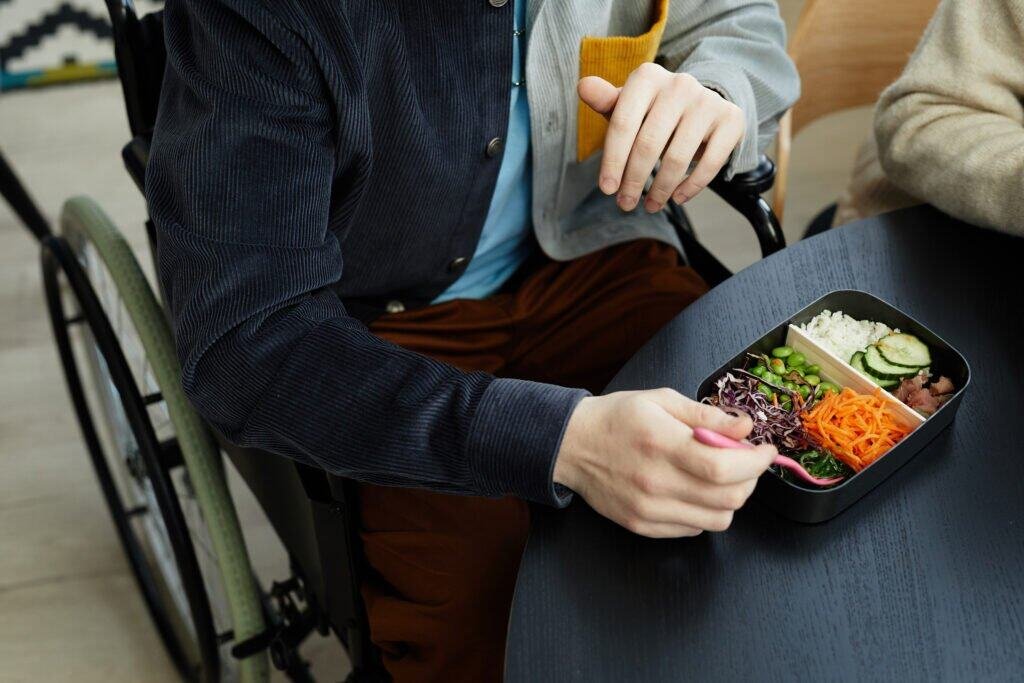 Person in wheelchair eating a nutritious meal with vegetables and healthy ingredients.