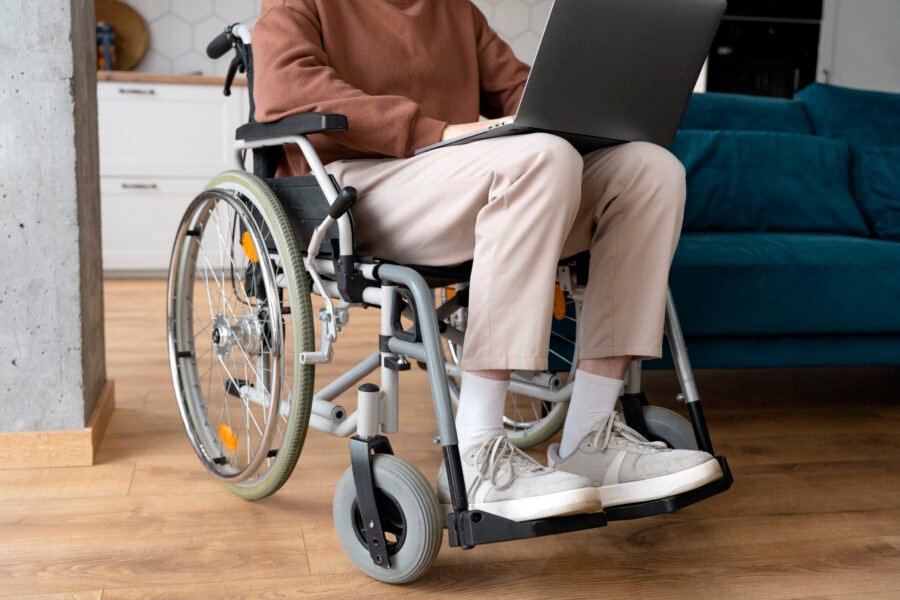 Wheelchair user working on a laptop at home.