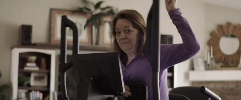 Woman using supported walk station for exercise at home.