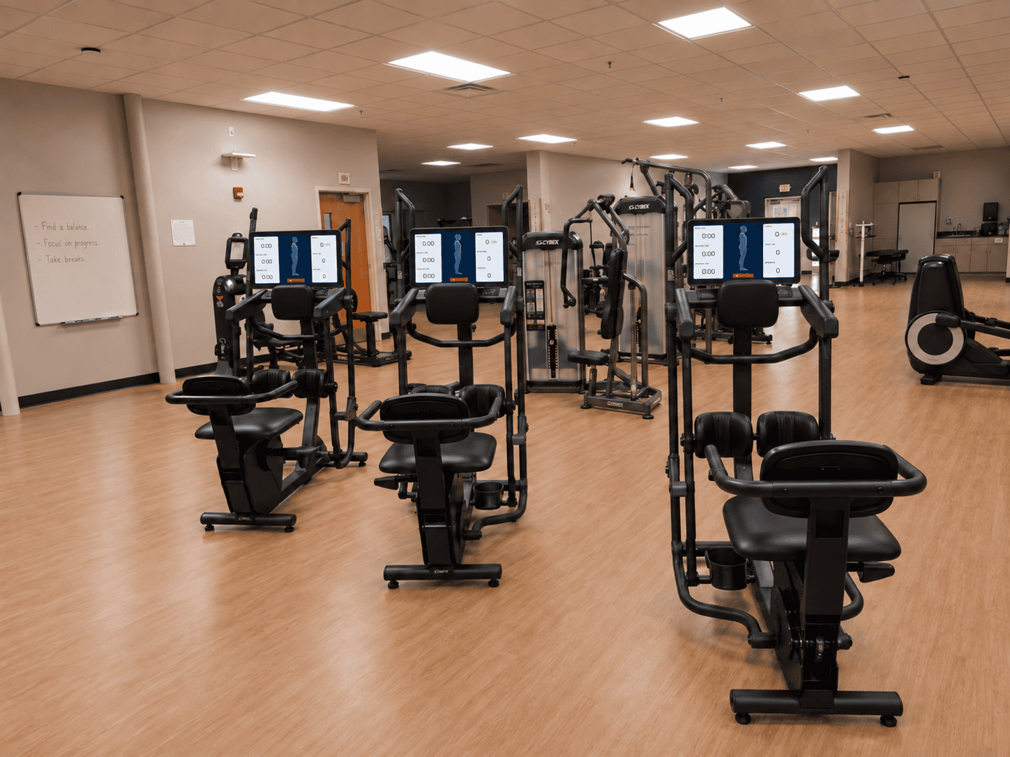 Three WalkPort Supported Walk Stations with app displays in a rehab facility gym